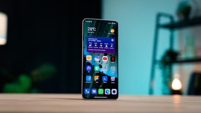 A imagem mostra um smartphone sobre uma mesa com ícones de redes sociais em sua tela