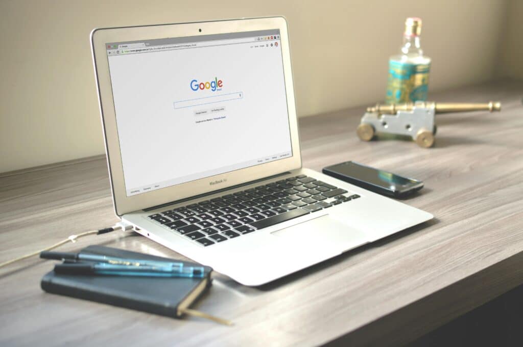 Mesa com caderno, celular e um notebook com a página do Google aberta para representar a importância do SEO.