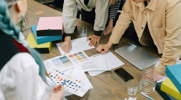Profissionais criativos conversando e escolhendo cores para um projeto em torno de uma mesa.
