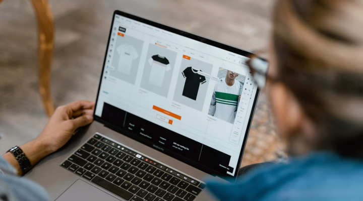 Two people collaborating on a laptop for t-shirt design and selection.