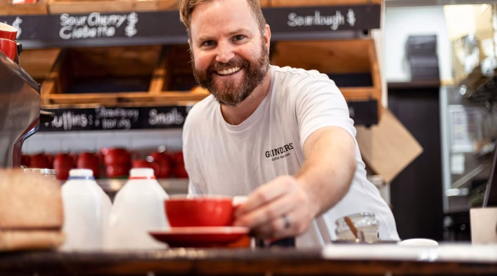 Photo by Snappr Um homem servindo um café em uma xícara vermelha, após consultoria em branding.