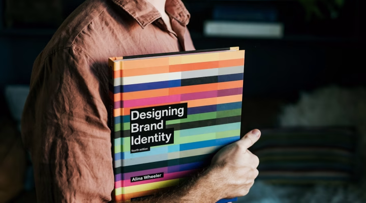 Photo by Hank Paul a man holding a book that says designing brand identity